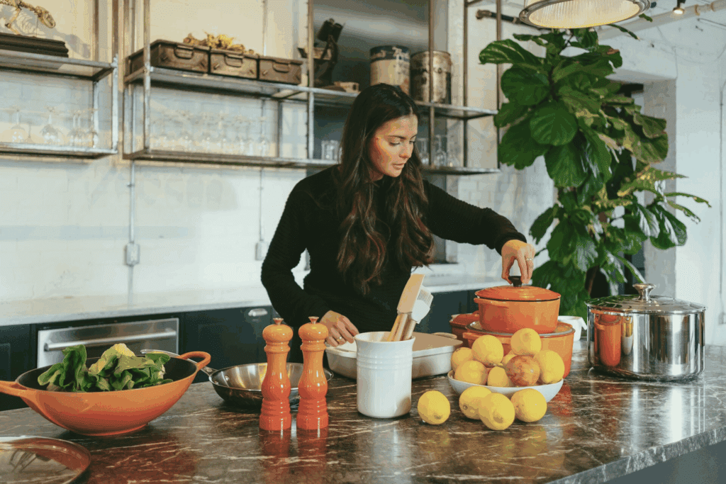 Donna che cucina in una cucina luminosa, trasformando la cucina terapeutica in un gesto di conforto e cura per sé stessa.