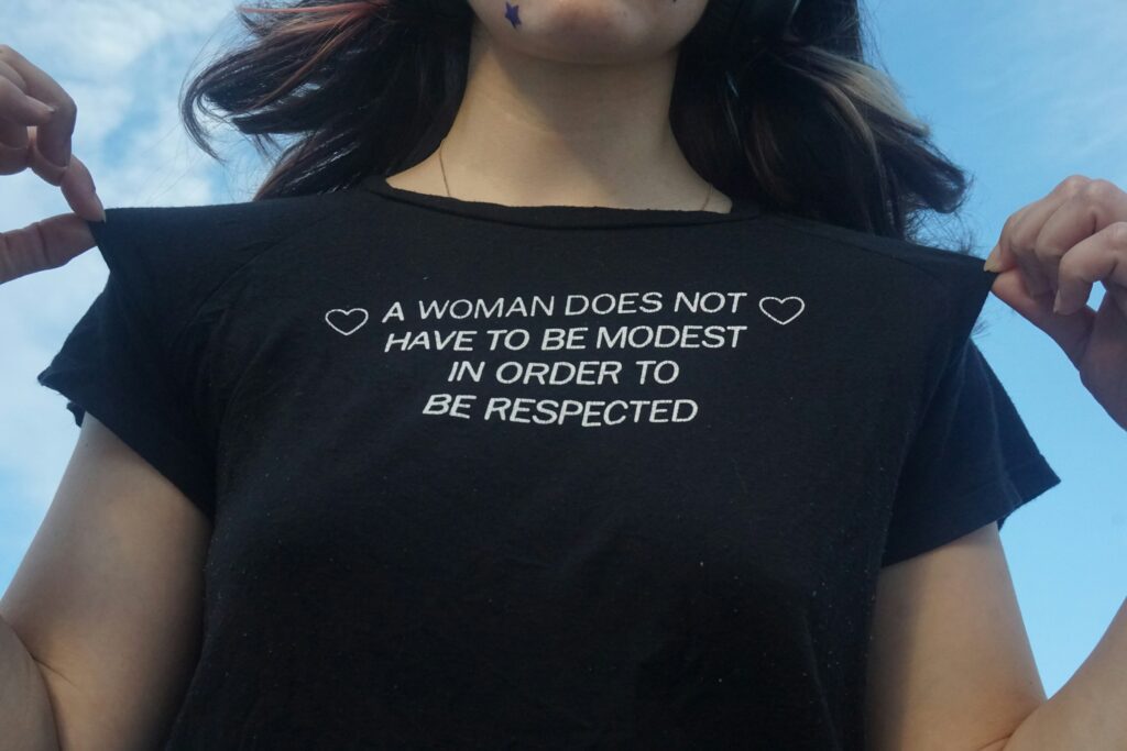 Donna che solleva la maglietta con una frase sull’autonomia e il rispetto, simbolo di imparare a dire no e affermare i propri confini.