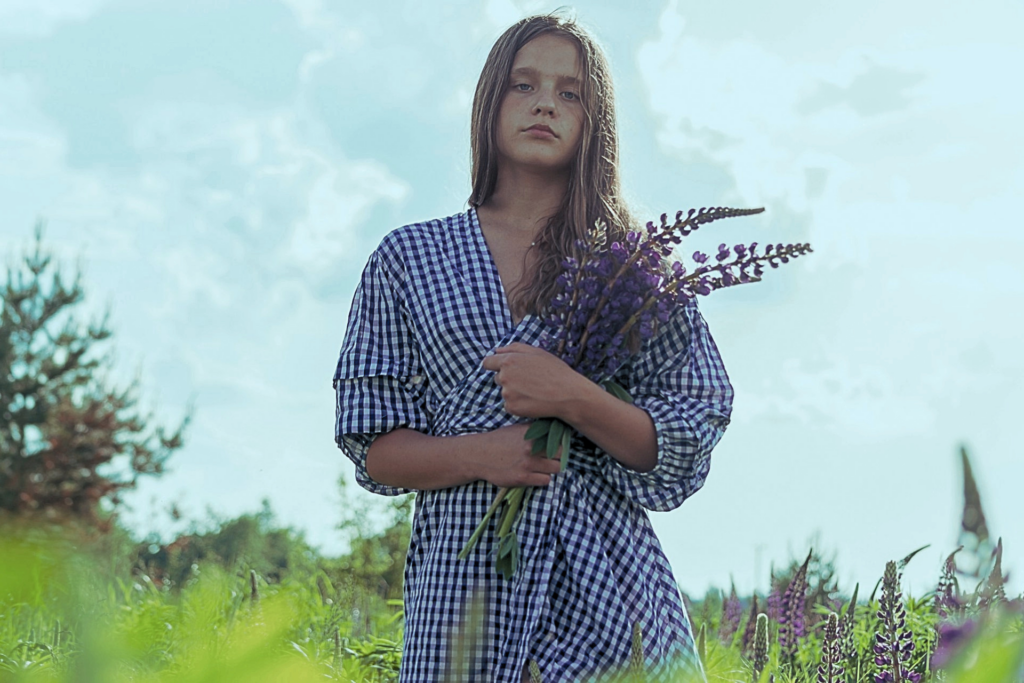 Ragazza in un campo con fiori che riflette, immagine che rappresenta come superare un periodo difficile attraverso introspezione e calma