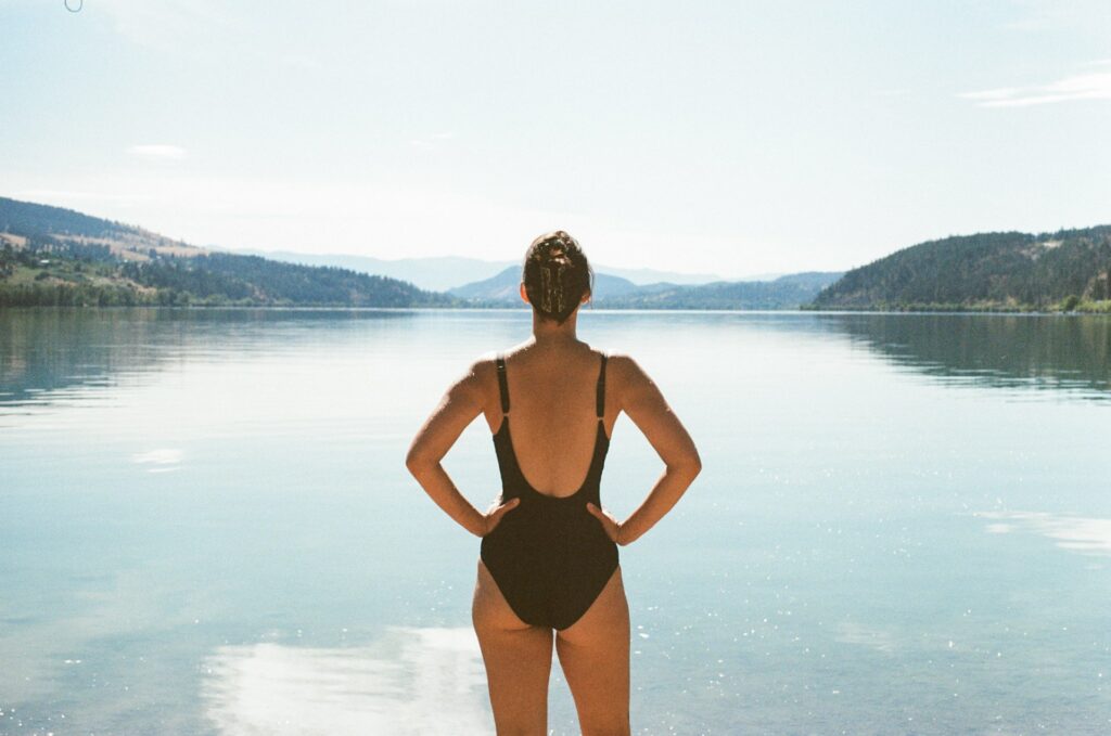 Donna davanti a un lago tranquillo mentre cerca calma e respiro dopo essersi sentita sopraffatta